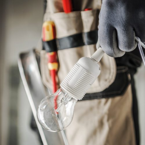 Electric Worker with Bulb in His Hand Preparing For a Light Point Installation. Close Up Photo. Industrial Concept.